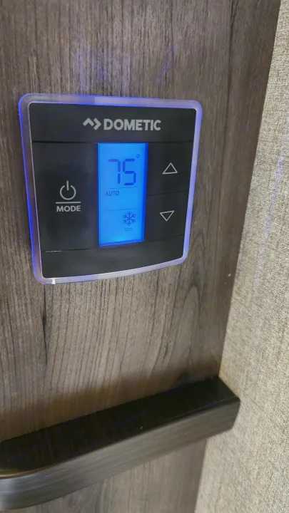 Dometic RV thermostat displaying 75°F (Cool/Auto) for an RV rental, ensuring comfortable climate control on wood paneling.. Jayco Jay Flight 2021