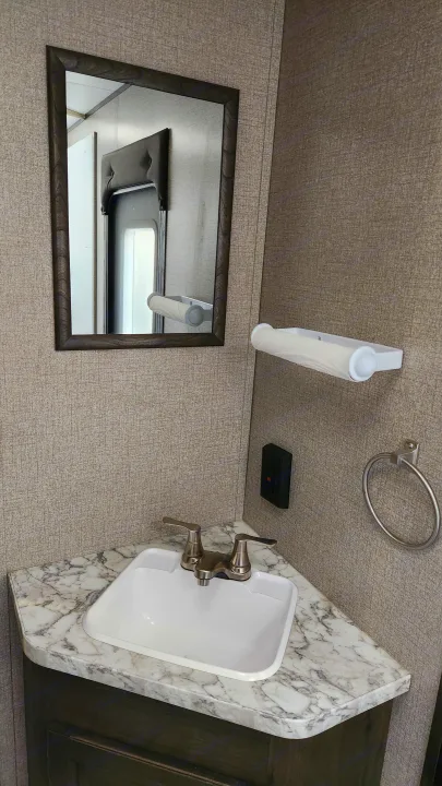 Compact RV rental bathroom vanity with sink, mirror, marble counter, GFCI outlet, and towel ring.. Jayco Jay Flight 2021