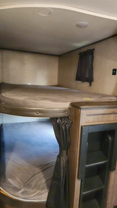 Cozy RV rental bunk beds with gray mattresses & storage unit. Perfect sleeping area for trips.. Jayco Jay Flight 2021