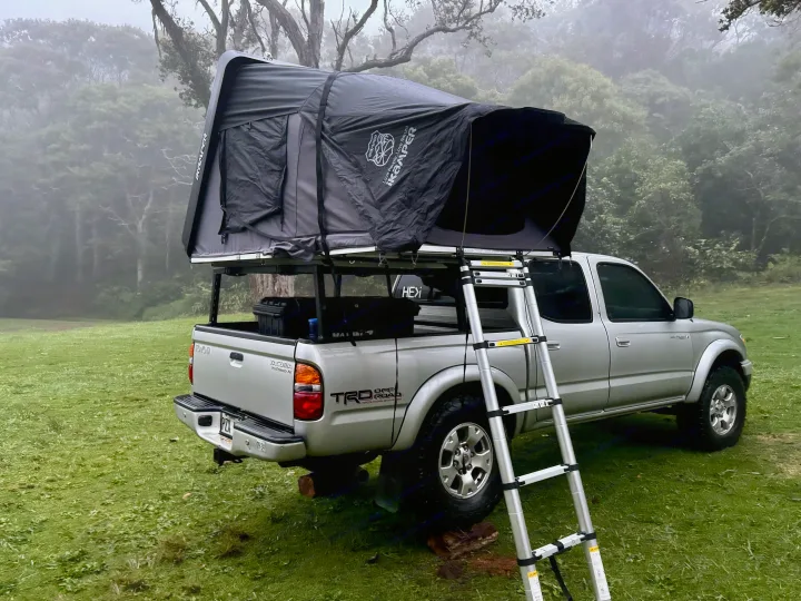 Silver truck with an iKamper rooftop tent deployed, perfect for an overland RV rental trip in a misty forest.. Rv Camper Tacoma 2002