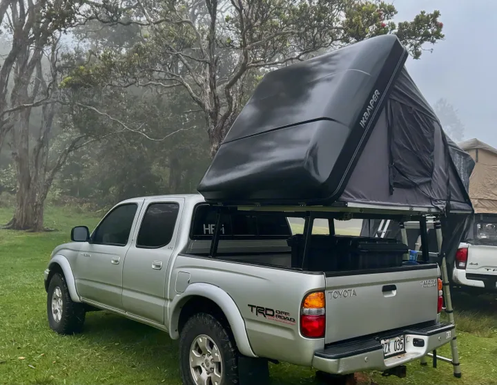 Toyota Tacoma with iKamper rooftop tent ready for camping in misty woods, a unique RV rental experience.. Rv Camper Tacoma 2002