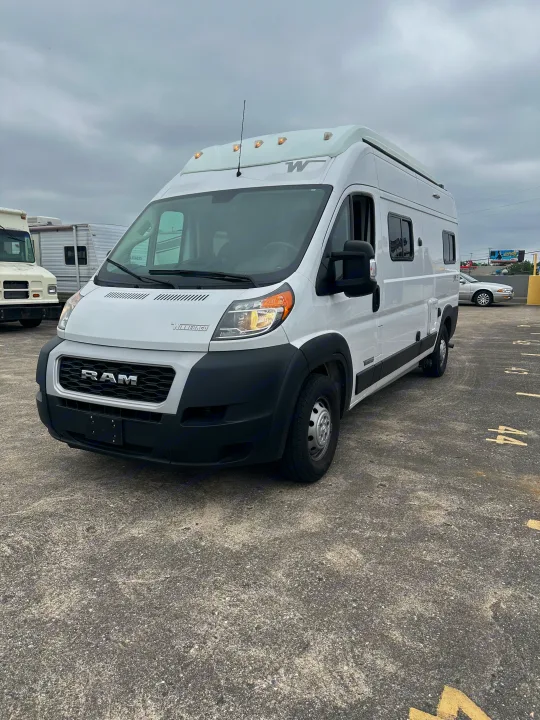 Front view of a white Winnebago Ram ProMaster RV rental van, featuring roof marker lights, parked on asphalt.. Winnebago Solis 2022