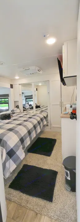 Cozy RV rental bedroom featuring a large bed with plaid comforter, two dogs, mirrored closets, and TV.. Crusader Crusader Fifth Wheel 2022