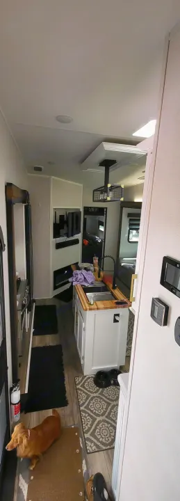 Modern RV rental interior: kitchen island, living room with TV, and a cute long-haired dog near the entrance.. Crusader Crusader Fifth Wheel 2022
