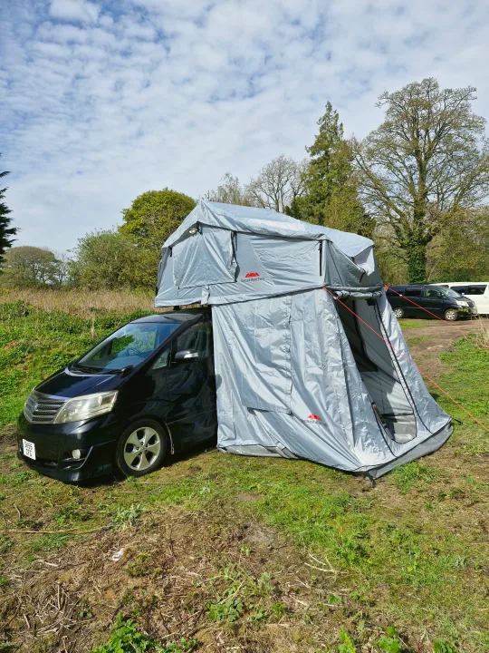 Unique RV rental option: Black minivan with Ventura rooftop tent and ground annex setup for camping.. Toyota Alphard 2024