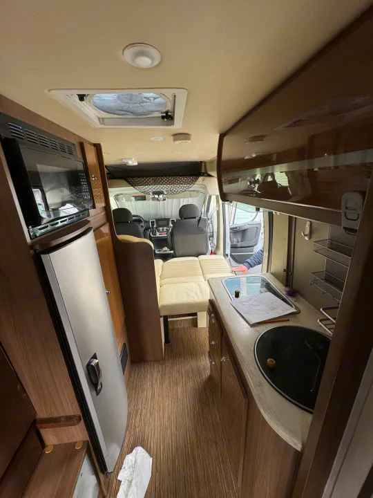 Inside an RV rental: a well-equipped camper van with a kitchenette, convertible seating, and overhead storage for your road trips.. Winnebago Travato 2015
