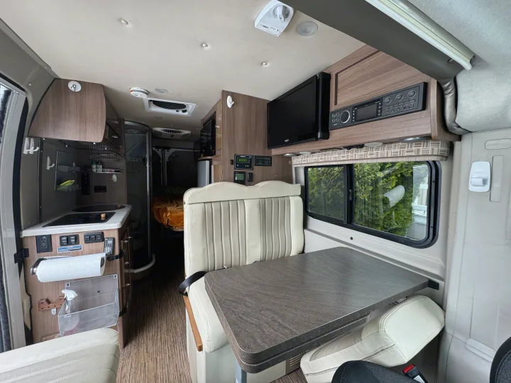 RV rental's versatile interior: well-equipped kitchen, dining area, and rear bed for comfortable road trips.. Winnebago Travato 2015