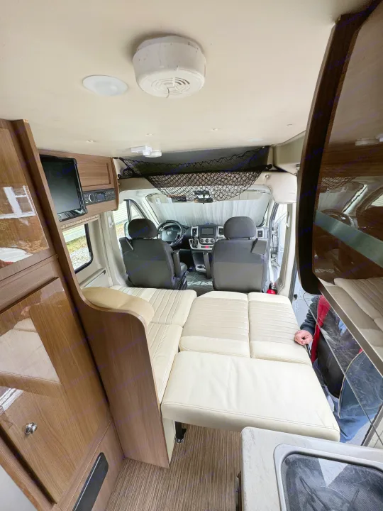 Interior of an RV rental: features convertible seating, driver's cabin, overhead storage, and a built-in TV.. Winnebago Travato 2015