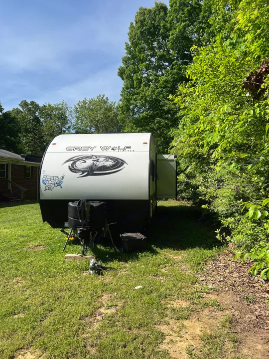 White Grey Wolf travel trailer, an ideal RV rental, parked on grass. US map sticker shows states visited.. Forest River Cherokee Grey Wolf 2023