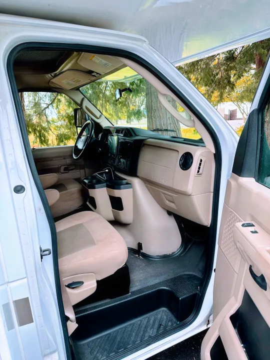 Interior of a white van, ready for rv rental, showing driver's seat, dashboard, and open door.. Thor Majestic 2015