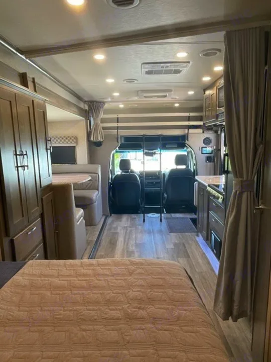 Spacious RV rental interior featuring a cozy bed, kitchen, dinette, and front cockpit, ready for your travel adventures.. Forest River Dynamax Isata 3 24FW 2023