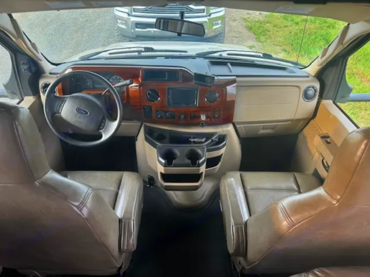 Inside an rv rental: the front cabin features a Ford steering wheel, wood-grain dashboard, and comfy tan seats.. Forest River 3051S Ford 2017