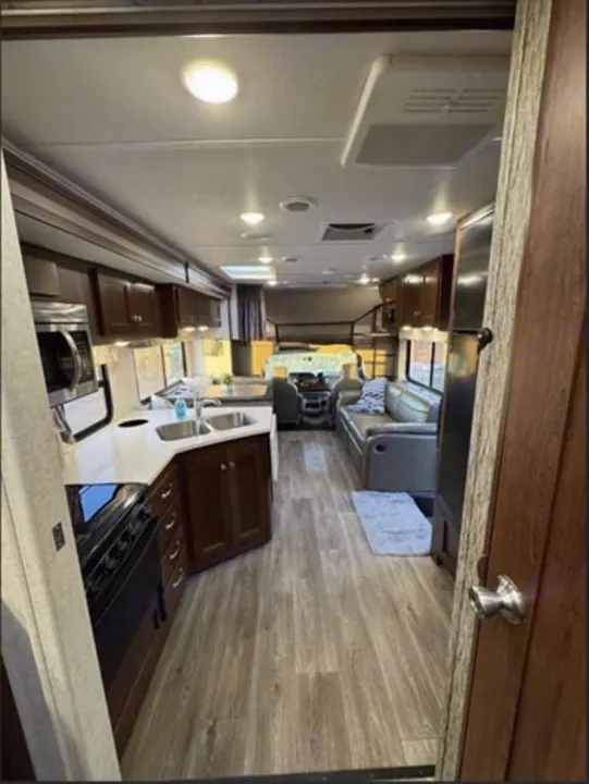 Full interior view of an RV rental, showing a modern kitchen, comfortable living space, and an overhead bunk.. Forest River 3051S Ford 2017