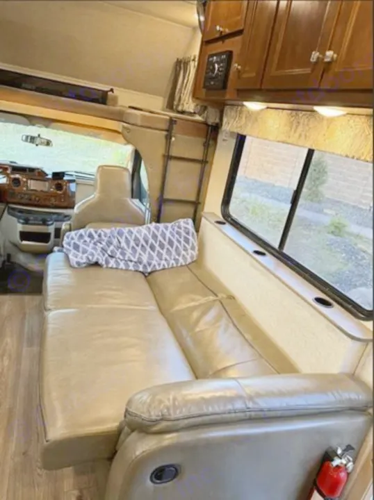 RV rental interior: Cozy living area with convertible sofa, overhead bunk bed, cabinets, window, & dashboard.. Forest River 3051S Ford 2017