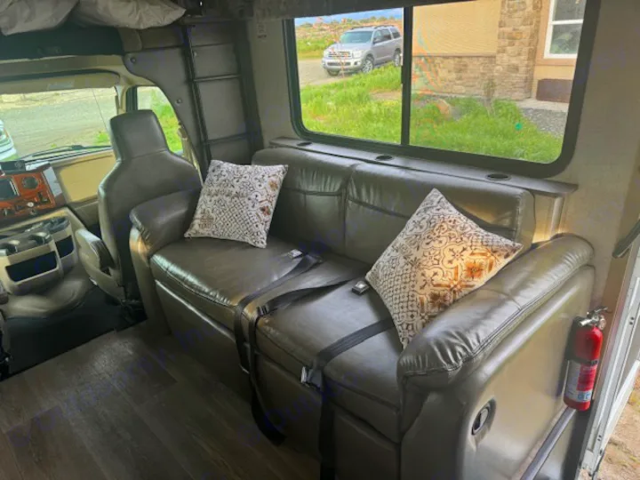 RV rental interior: a comfy brown sofa with decorative pillows, front cockpit seats, and fire extinguisher for safety.. Forest River 3051S Ford 2017