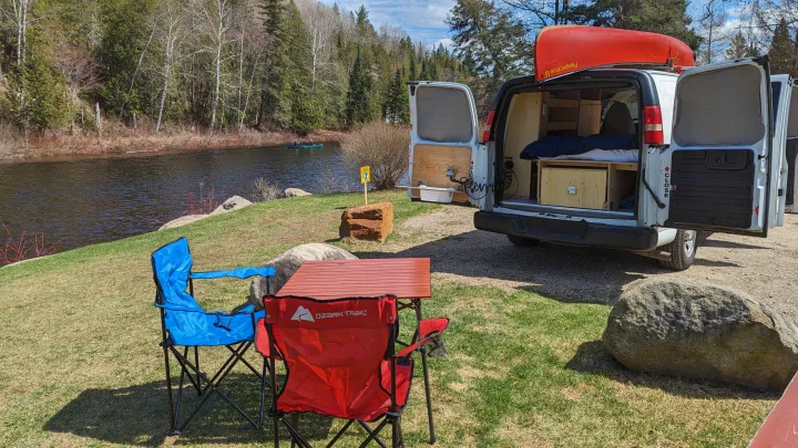 Enjoy the outdoors with this RV rental campervan by a scenic river, complete with a canoe, camping chairs, and table.. Chevrolet Express 2009