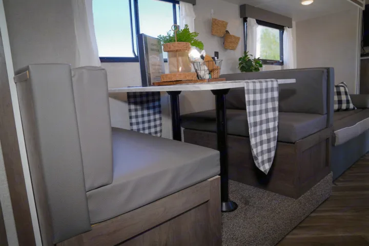 Cozy RV rental interior showcasing a modern dinette area with grey upholstered benches and a checkered table runner.. Forest River EVO 2021