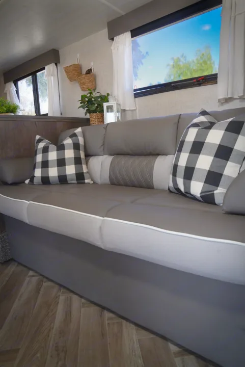 Inviting RV rental interior: grey sofa with plaid pillows, bright windows, and modern decor details.. Forest River EVO 2021