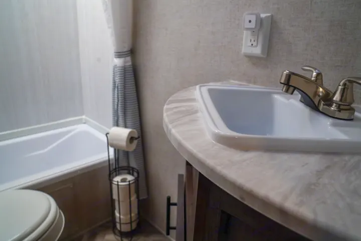 Explore RV rental comfort: a compact bathroom featuring sink, toilet, tub, and shower, designed for your travels.. Forest River EVO 2021