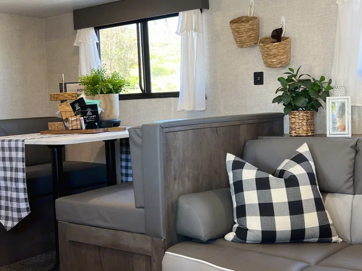 Inviting RV rental interior: dinette with checkered runner, cozy sofa, and stylish decor elements.. Forest River EVO 2021