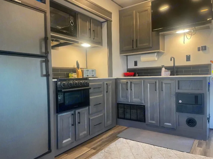 This RV rental offers a well-equipped kitchen: fridge, microwave, oven, sink, and ample grey cabinet storage.. Heartland 265 2021