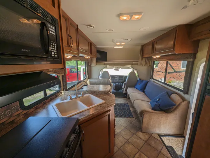 RV rental interior: well-appointed kitchen with microwave, double sink, and a comfortable living area with sofa.. Thor Motor Coach Four Winds 2014