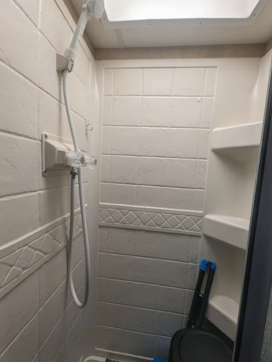 RV rental's compact shower: a clean, functional space with handheld shower head and built-in shelving.. Thor Motor Coach Four Winds 2014