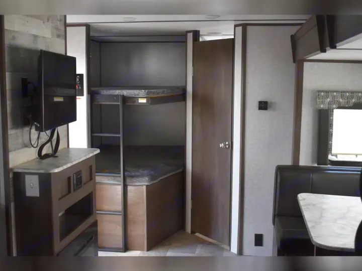 RV rental interior featuring bunk beds, TV, and dining area, ideal for family travel.. Dutchmen Coleman Light 2021