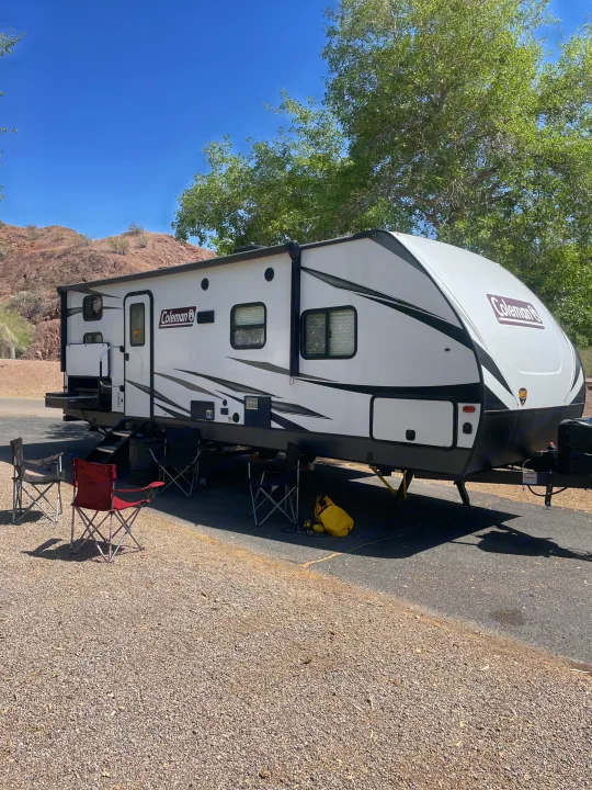 Coleman RV rental at a sunny desert campsite with chairs set up. Ready for outdoor adventures.. Dutchmen Coleman Light 2021