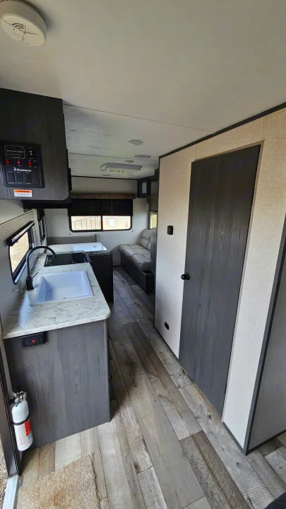 Bright RV rental interior with a modern kitchenette, dinette, lounge, and wood-look flooring, ready for adventure.. Aspen Trail LE 2022