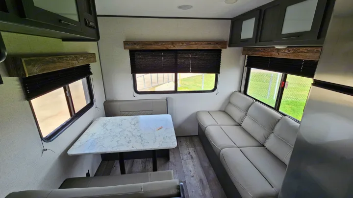 Bright RV rental interior: dinette with marble table, comfy sofa, and wood-look accents. Great for camper adventures!. Aspen Trail LE 2022