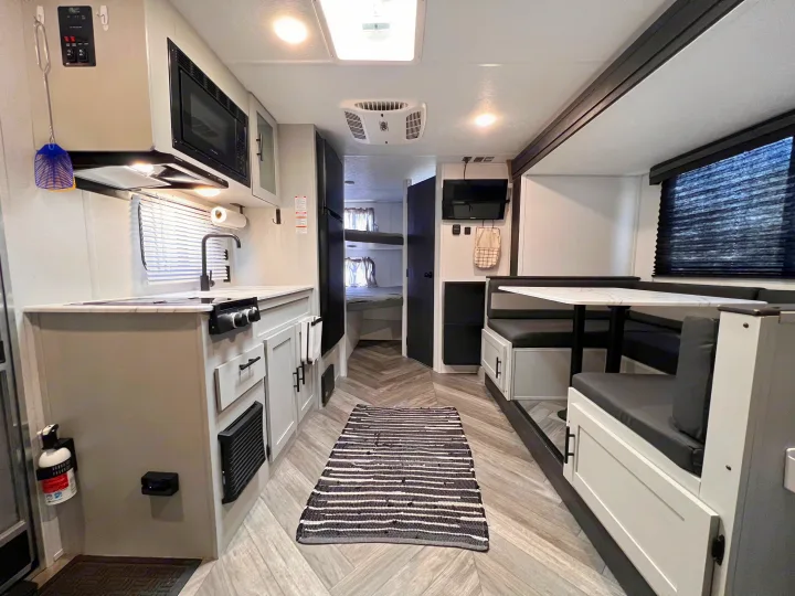 Modern RV rental interior showing a kitchen, dining area with a table, and bunk beds in the back for comfortable travel.. Wildwood FSX 2021