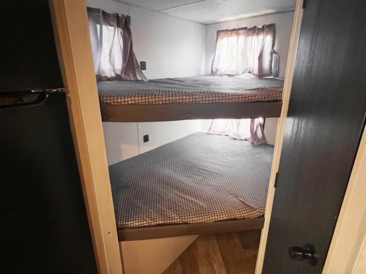 Cozy RV rental interior featuring spacious bunk beds with patterned mattresses and windows, ideal for compact travel.. Wildwood FSX 2021