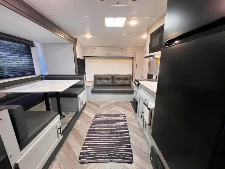 Bright RV rental interior with a contemporary kitchen, dinette, and versatile sofa bed for comfortable travel.. Wildwood FSX 2021