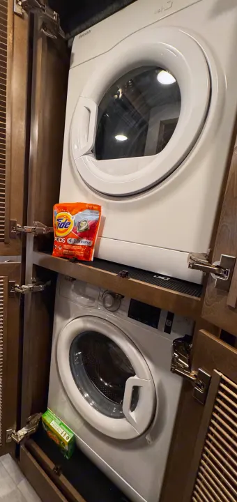 Compact stacked laundry appliances in an RV rental. White washer/dryer with Tide Pods and dryer sheets for convenience.. Renegade Verona 40 VRB 2024