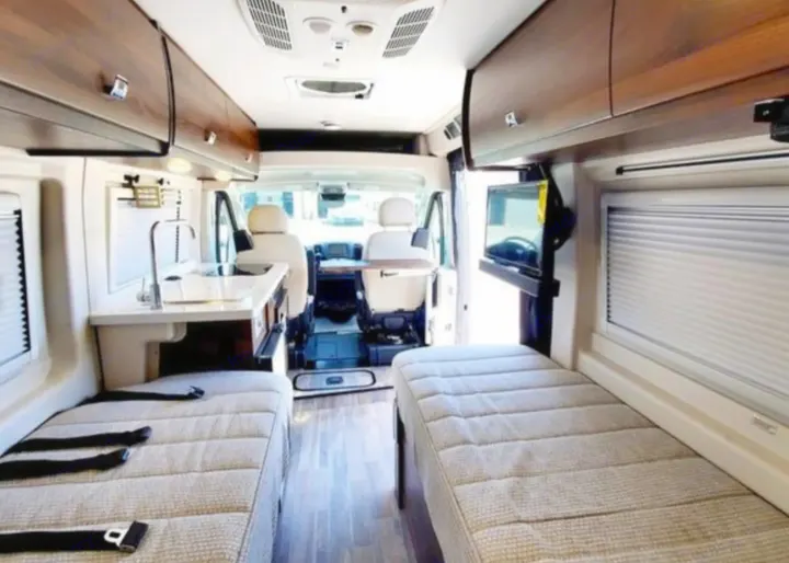 Spacious RV rental interior: showing beds, a compact kitchen, and TV. A well-equipped camper van for your travels.. Winnebago Travato 2022