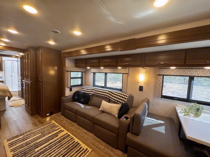Comfortable RV rental: a bright interior featuring a spacious living area with sofa, windows, and dining booth.. Renegade Verona 40 VRB 2024