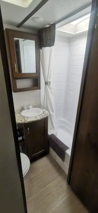 RV rental bathroom: A compact space with sink, medicine cabinet, shower/tub combo, and toilet visible.. Keystone RV Passport 2019