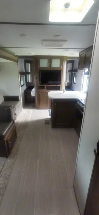 Spacious RV rental interior with full kitchen, living area, and private bedroom beyond.. Keystone RV Passport 2019