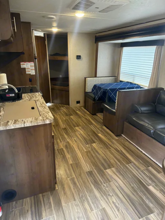 Spacious RV rental interior: kitchen, dinette, bunk beds, sofa, and wood-look floors, perfect for travel.. Shasta 26db 2020