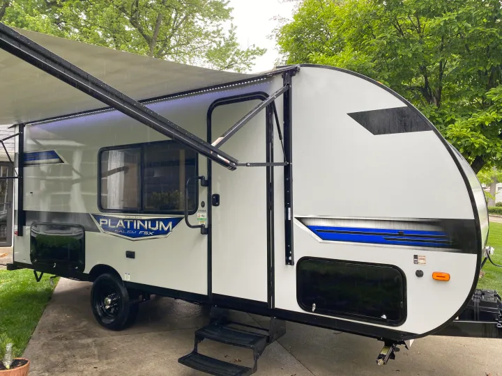 Rainy day RV rental: A white/grey Forest River Salem FSX travel trailer with its awning extended and lights on.. Forest River Salem FSX Plantium 2022