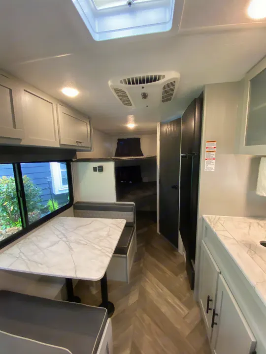 Bright rv rental interior featuring a dining area, kitchen, refrigerator, bunk beds, and herringbone flooring.. Forest River Salem FSX Plantium 2022