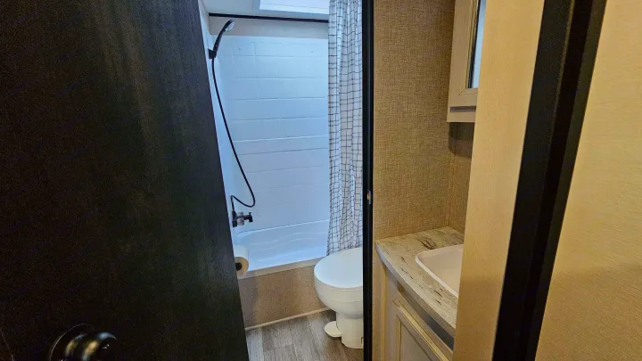 This RV rental features a compact bathroom with a shower/tub, toilet, and vanity with sink and mirror for comfortable travel.. Jayco Jay Flight Baja Edition 2023