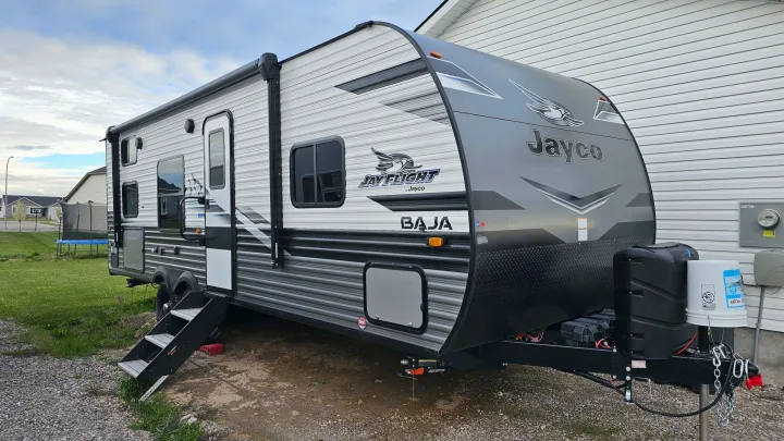 Sleek Jayco travel trailer, ready for your next rv rental adventure. Parked next to a home in a suburban setting.. Jayco Jay Flight Baja Edition 2023