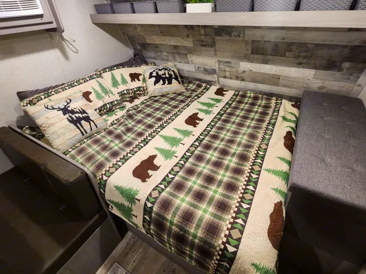 Cozy RV rental bedroom with rustic plaid and nature-themed bedding. Features bear, deer, & tree designs for a comfy stay.. Other 17B 2023