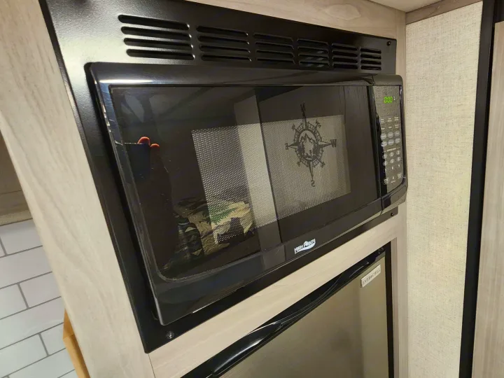 RV rental kitchen featuring a built-in High Pointe microwave oven with a compass design and an Ever Chill refrigerator below.. Other 17B 2023