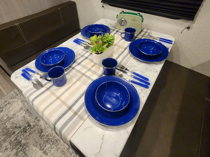 Cozy RV rental dinette with blue enamelware tableware, plaid runner, and vintage radio. Perfect for camping meals!. Other 17B 2023