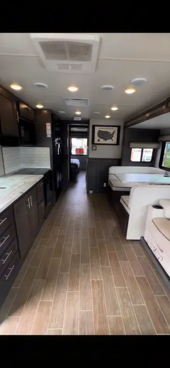 Bright RV rental interior featuring a well-equipped kitchen, dining area, and hallway to a private bedroom.. Forest River Georgetown 2022