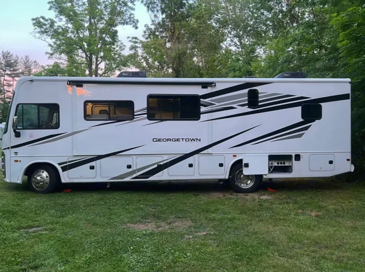 White motorhome RV rental parked on green grass with black and gray stripe graphics.. Forest River Georgetown 2022