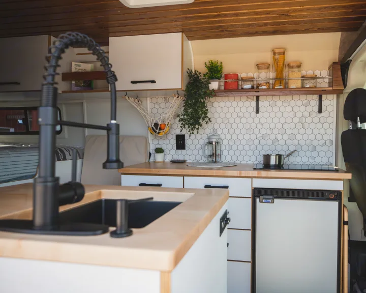 Modern RV rental kitchen with sleek faucet, wood counters, hexagon backsplash, and full amenities, perfect for travel.. Dodge Ram Promaster 2021